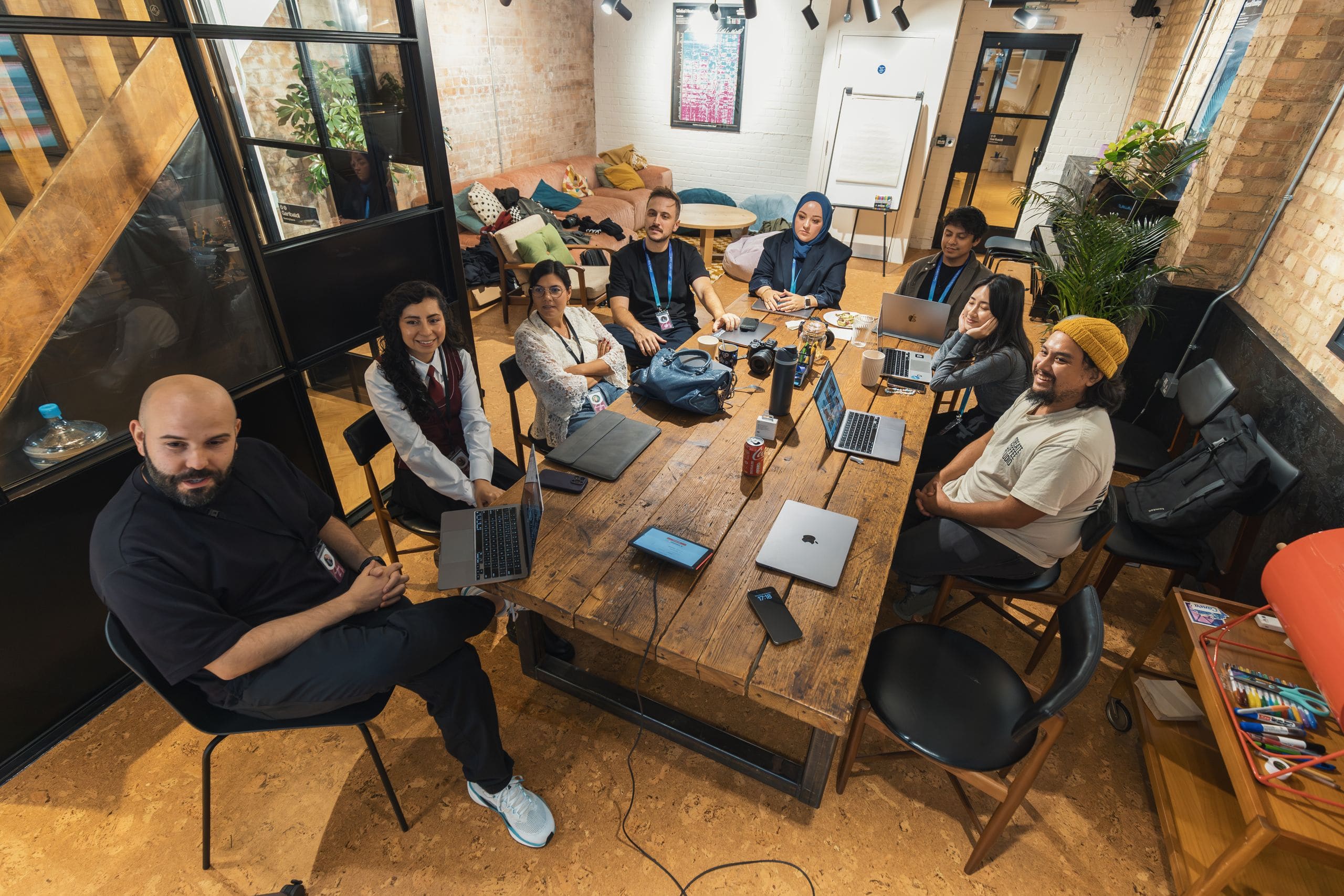 A working team of many nationalities and ages reviewing plans together at a large table in a bright Vancouver office